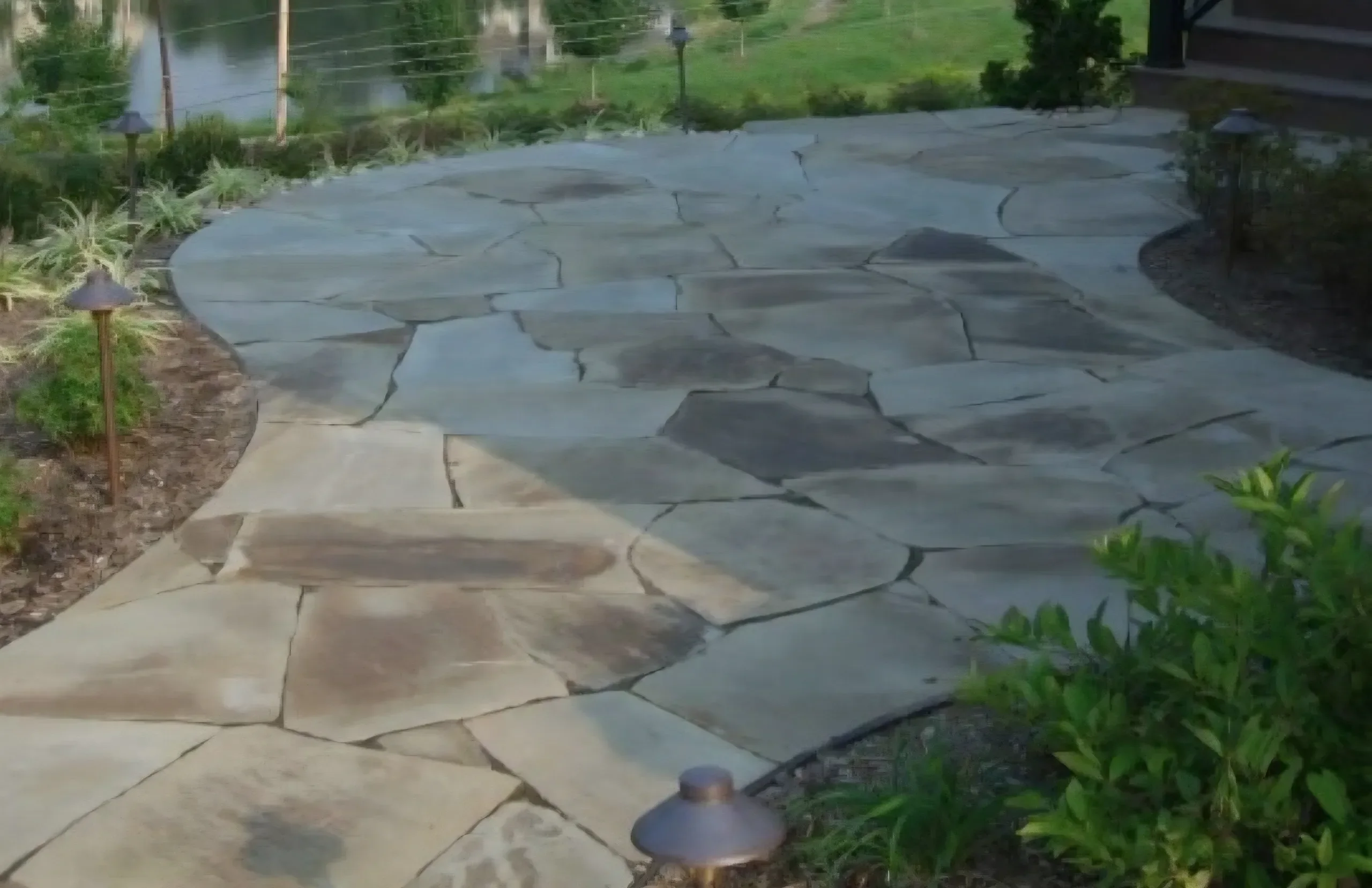 A winding flagstone path with landscape lighting guides visitors toward a waterfront view.